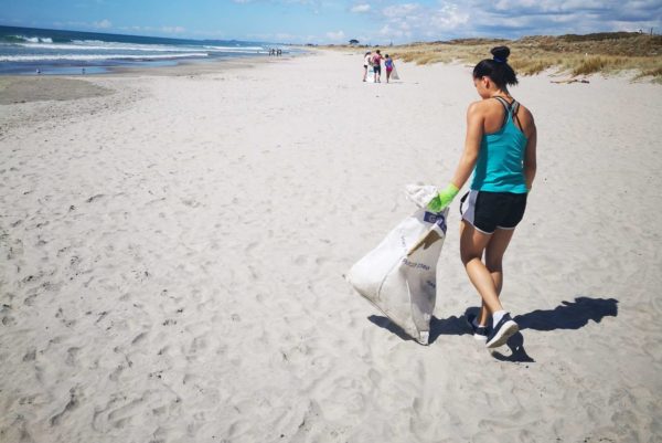 Young university student walks Mount Maunganui Beach with a rubbish bag on a Love Your Coast beach clean up