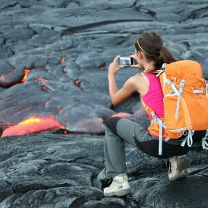 Student on tour in Hawaii photographing lava on a volcano